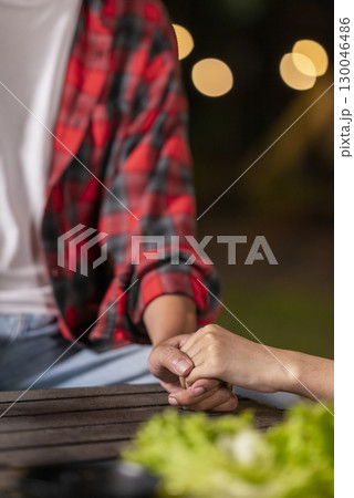 Closeup view of the connection between a couple holding hands. The scene of love, togetherness, or cheating in a relaxed setting. The scene of the lifestyle of camping in a natural setting 130046486