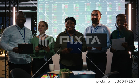 Portrait of diverse business colleagues reviewing monthly insights and performance indicators within the company. Employees conducting evaluations and sharing ideas for goal setting. Camera A. 130047157