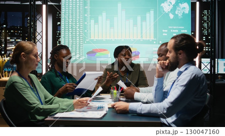 Multiethnic group of advisors reviewing data insights and financial situation on papers, preparing updates for the shareholders and establishing the project agenda and objectives. Camera A. 130047160