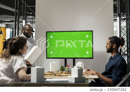 Diverse engineering staff study zoning regulations next to green screen on TV, city planning residential construction for urban development during briefing session. Property investment. 130047262