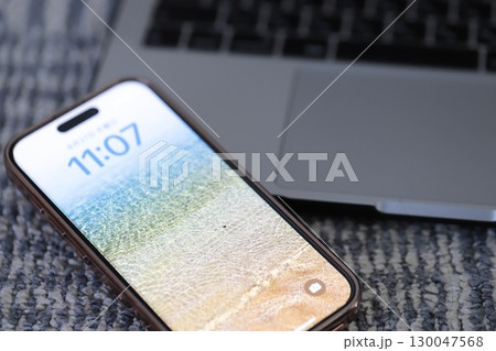 カーペットの上に置いたノートパソコンとスマホ 130047568