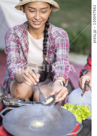 Indonesian southeast asian couple preparing for an outdoor meal, showcasing a portable stove and various ingredients. The scene of the lifestyle of enjoying food in a natural setting Indonesian southeast asian couple preparing for an outdoor meal, showcasing a portable stove and various ingredients. The scene of the lifestyle of enjoying food in a natural setting 130047662