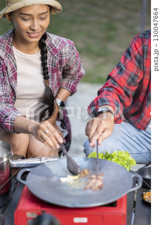 Indonesian southeast asian couple preparing for an outdoor meal, showcasing a portable stove and various ingredients. The scene of the lifestyle of enjoying food in a natural setting Indonesian southeast asian couple preparing for an outdoor meal, showcasing a portable stove and various ingredients. The scene of the lifestyle of enjoying food in a natural setting 130047664
