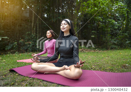 Indonesian southeast asian women in a sporty outfit relaxing and meditating zen-like on a fitness mat in a public park outdoors. Concept of a Healthy active lifestyle Indonesian southeast asian women in a sporty outfit relaxing and meditating zen-like on a fitness mat in a public park outdoors. Concept of a Healthy active lifestyle 130048432