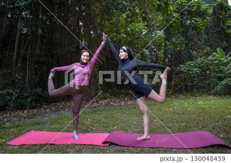 Indonesian southeast asian women in a sporty outfit practice exercise on a mat in a public park outdoors. Concept of a Healthy active lifestyle 130048439