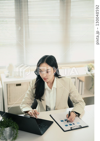 Concentrated female executive checking reports at workplace 130048592