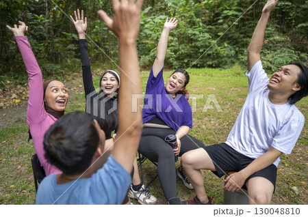 Indonesian southeast asian people in a sporty outfit, stacking hands together before practice exercise in a public park outdoors. Concept of a Healthy active lifestyle 130048810