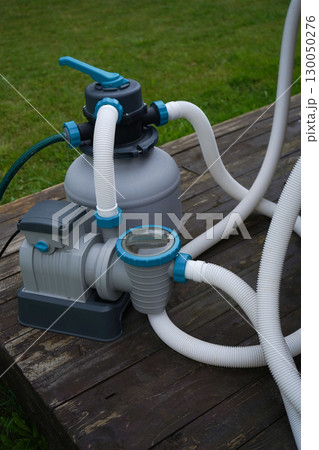A pump with a filter for a private pool that stands outside on a sunny warm summer day. A pump with a filter for a private pool that stands outside on a sunny warm summer day. 130050276