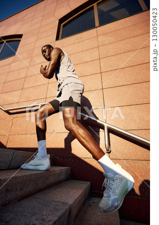 Athletic man engaged in outdoor stair workout on a sunny day Athletic man engaged in outdoor stair workout on a sunny day 130050423