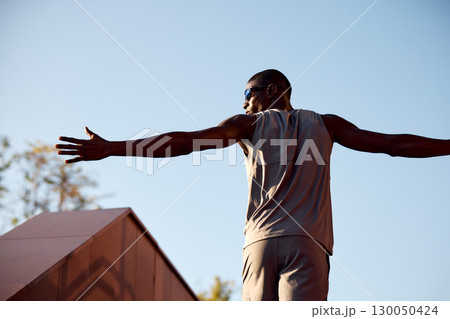 Athletic man exercising outdoors under blue sky during daytime 130050424