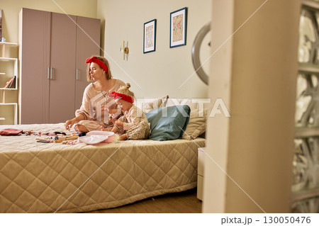 Mother and daughter bonding while playing together in a cozy bedroom Mother and daughter bonding while playing together in a cozy bedroom 130050476
