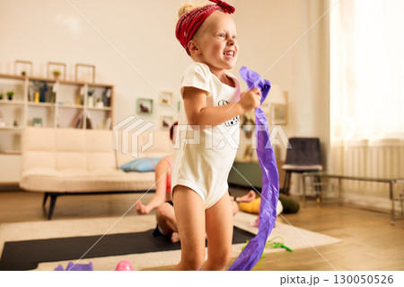 Energetic child playing indoors with a scarf in a sunny living room Energetic child playing indoors with a scarf in a sunny living room 130050526