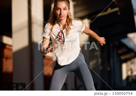 Young woman exercising outdoors during sunset in urban environment Young woman exercising outdoors during sunset in urban environment 130050754