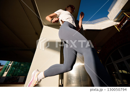 Woman running in urban environment in the sunlight Woman running in urban environment in the sunlight 130050794