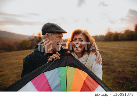 Senior couple flying a kite during warm autumn evening. Senior couple flying a kite during warm autumn evening. 130051379