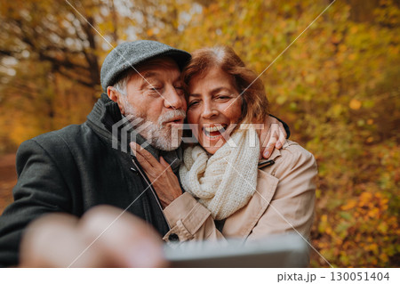 Senior man and woman taking selfie in the middle of autumn forest. Senior man and woman taking selfie in the middle of autumn forest. 130051404