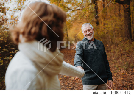 Happy elderly woman walking in forest with her husban, holding hands. 130051417