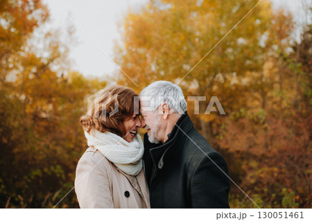 Romantic walk through fall forest by senior couple. 130051461