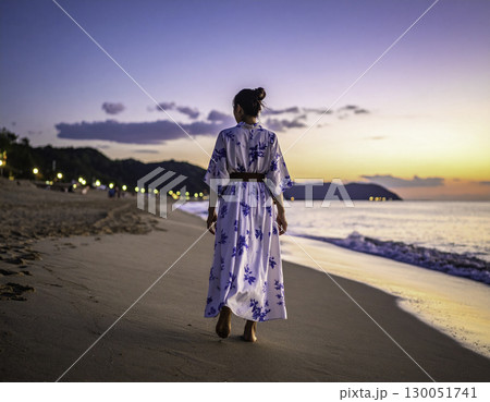 夕暮れの海辺を歩く女性の後ろ姿 130051741