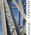 Close-up of a steel bridge structure with rivets in focus against a clear blue sky background 130053044