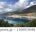 Scenic view of marina with sailboats against mountains and clouds reflecting on water 130053046