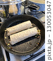 Burritos cooking in pan on kitchen stove, showcasing cooking process and Mexican cuisine 130053047