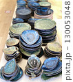 Ceramic tableware with blue green glazed finish stacked on wooden surface 130053048