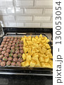 Raw meatballs and seasoned potato cubes on a tray before baking in a home kitchen setting 130053054