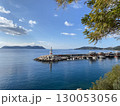 Scenic coastal view with lighthouse and harbor under clear sky, ideal for background use 130053056
