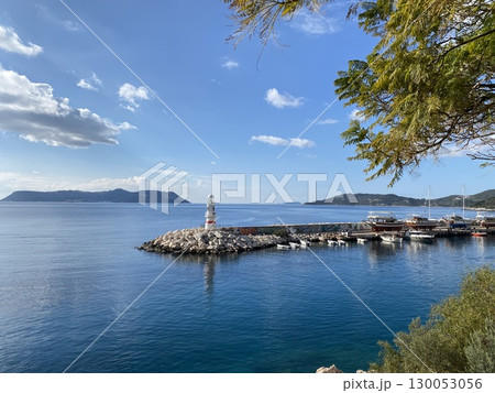 Scenic coastal view with lighthouse and harbor under clear sky, ideal for background use Scenic coastal view with lighthouse and harbor under clear sky, ideal for background use 130053056