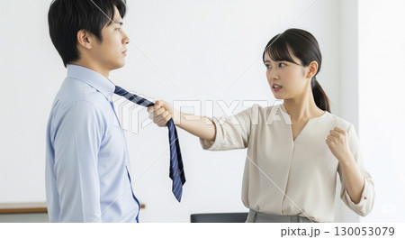 ネクタイを引っ張って怒りをぶつけるビジネスウーマン 130053079