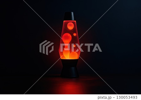 Red lava lamp glowing in dark room with floating wax blobs inside glass container, retro ambient  130053493