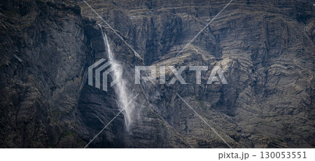Flowing waterfall cascading down rugged cliffs of Cirque de Gavarnie in the Pyrenees, showcasing 130053551