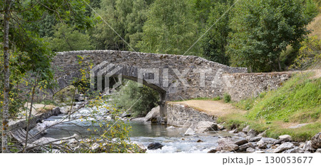 Scenic view of Pyrenees stone bridge over Gavarnie stream at dawn, surrounded by lush greenery and Scenic view of Pyrenees stone bridge over Gavarnie stream at dawn, surrounded by lush greenery and 130053677