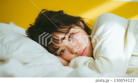 枕に寄り添って横になる女性 130054127