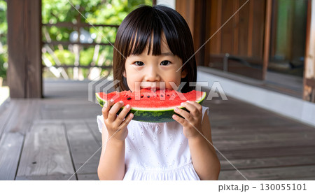 縁側に座って美味しそうに喜んでスイカを食べる幼くて可愛い日本人の女の子 130055101