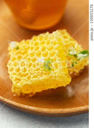 Fresh honeycomb with flower on wooden plate and honey in glass jar 130055278