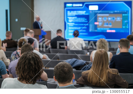 Business seminar with attendees facing screen during speaker presentation in conference room 130055517