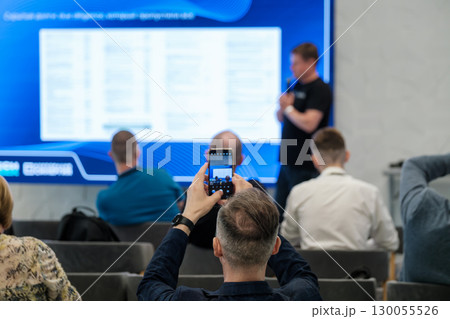 Man photographing presentation using phone at a conference event 130055526
