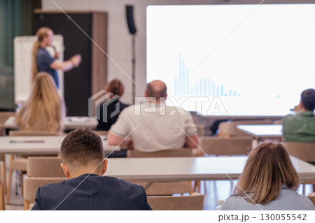 People attending a business presentation with speaker and screen in modern workspace 130055542