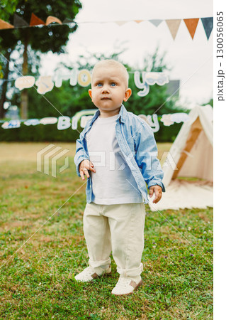 A cute toddler enjoying a delightful outdoor birthday party filled with charming handmade decorations and an adorable play tent, surrounded by friends and family, creating wonderful memories 130056065