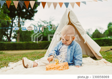 A Delightful and Sweet Birthday Celebration A Joyful Toddler Cheerfully Enjoying a Delicious Cake in a Cozy Outdoor Setting Adorned with Colorful and Festive Decorations for the Special Day 130056069