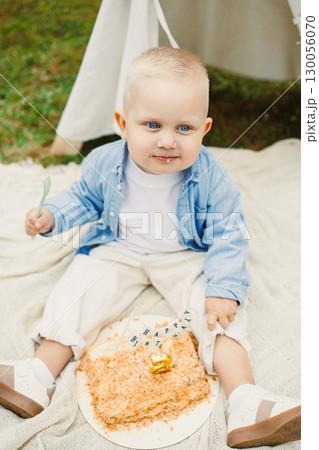 On this sunny day, a baby celebrates their first birthday outdoors with loving family and friends, a colorful cake, capturing the joyful emotions of childhood on this special occasion On this sunny day, a baby celebrates their first birthday outdoors with loving family and friends, a colorful cake, capturing the joyful emotions of childhood on this special occasion 130056070
