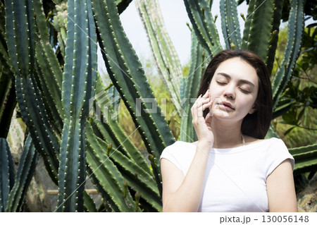 サボテンの前に立つきれいな女性 130056148