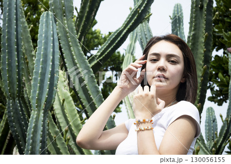 サボテンの前に立つきれいな女性 130056155