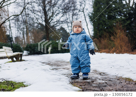 An Adorable Toddler Dressed in a Cozy Winter Outfit is Playing Joyfully in a Snowy Park This Scene Captures the Pure Joy and Innocence of Childhood in a Magical Winter Wonderland Environment 130056172