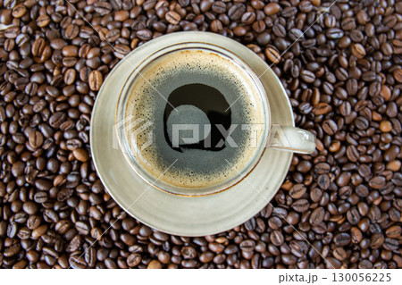 Green cup of coffee and roasted coffee beans background. Top view. 130056225