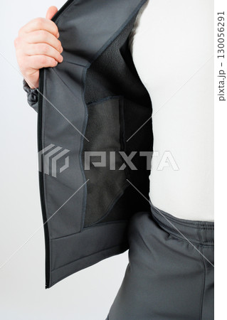 This is a closeup view of a stylish black jacket that features an open interior, showcasing its functional pockets along with modern design elements that enhance its visual appeal and practicality 130056291