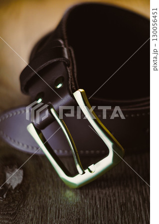 This is a closeup shot featuring a stylish leather belt that is adorned with a metallic buckle, an essential piece for enhancing any fashion accessory collection, making it perfect for any outfit 130056451