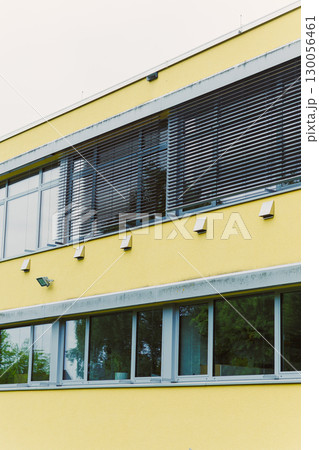 This contemporary architecture features a striking yellow building with uniquely textured walls and large, inviting windows, enhancing its overall design and creating impressive visual appeal 130056461